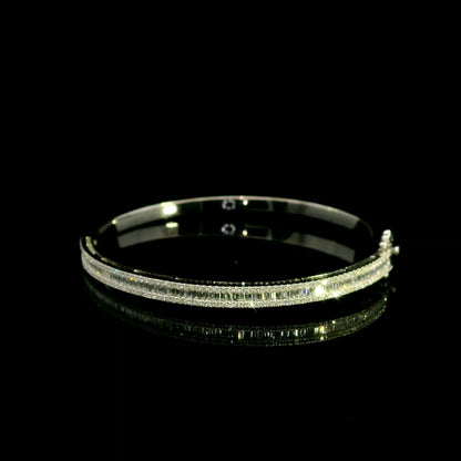 18K white gold diamond bangle with a central row of baguette diamonds framed by round brilliant diamonds and secure hinged clasp
