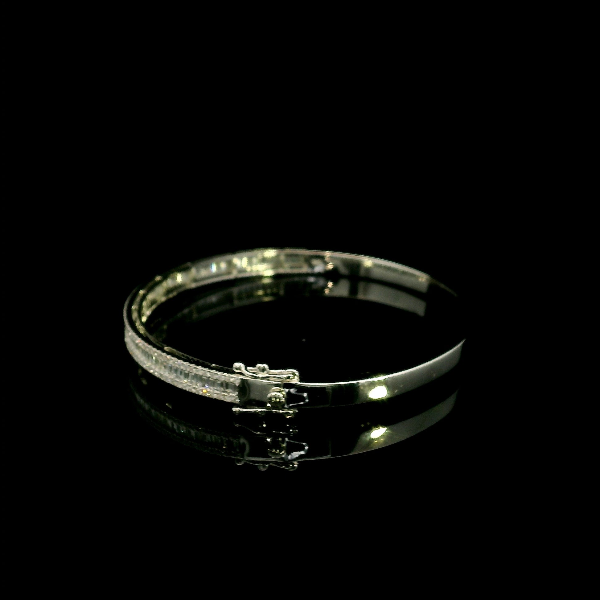 18K white gold diamond bangle with a central row of baguette diamonds framed by round brilliant diamonds and secure hinged clasp