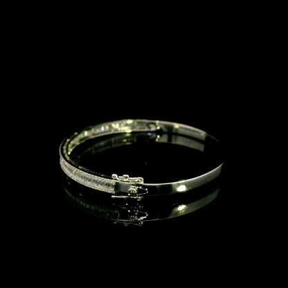18K white gold diamond bangle with a central row of baguette diamonds framed by round brilliant diamonds and secure hinged clasp