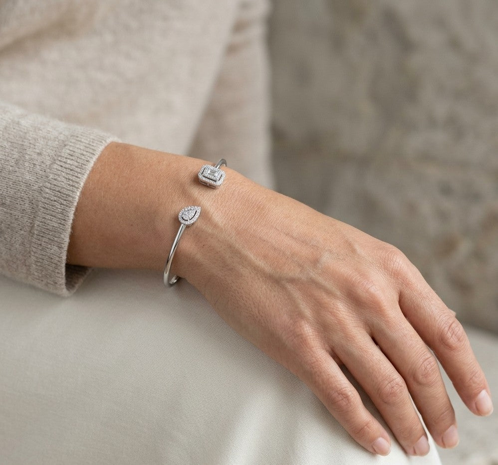 Geometric diamond open bangle in 18K white gold with contrasting pear-shaped and rectangular diamond motifs.