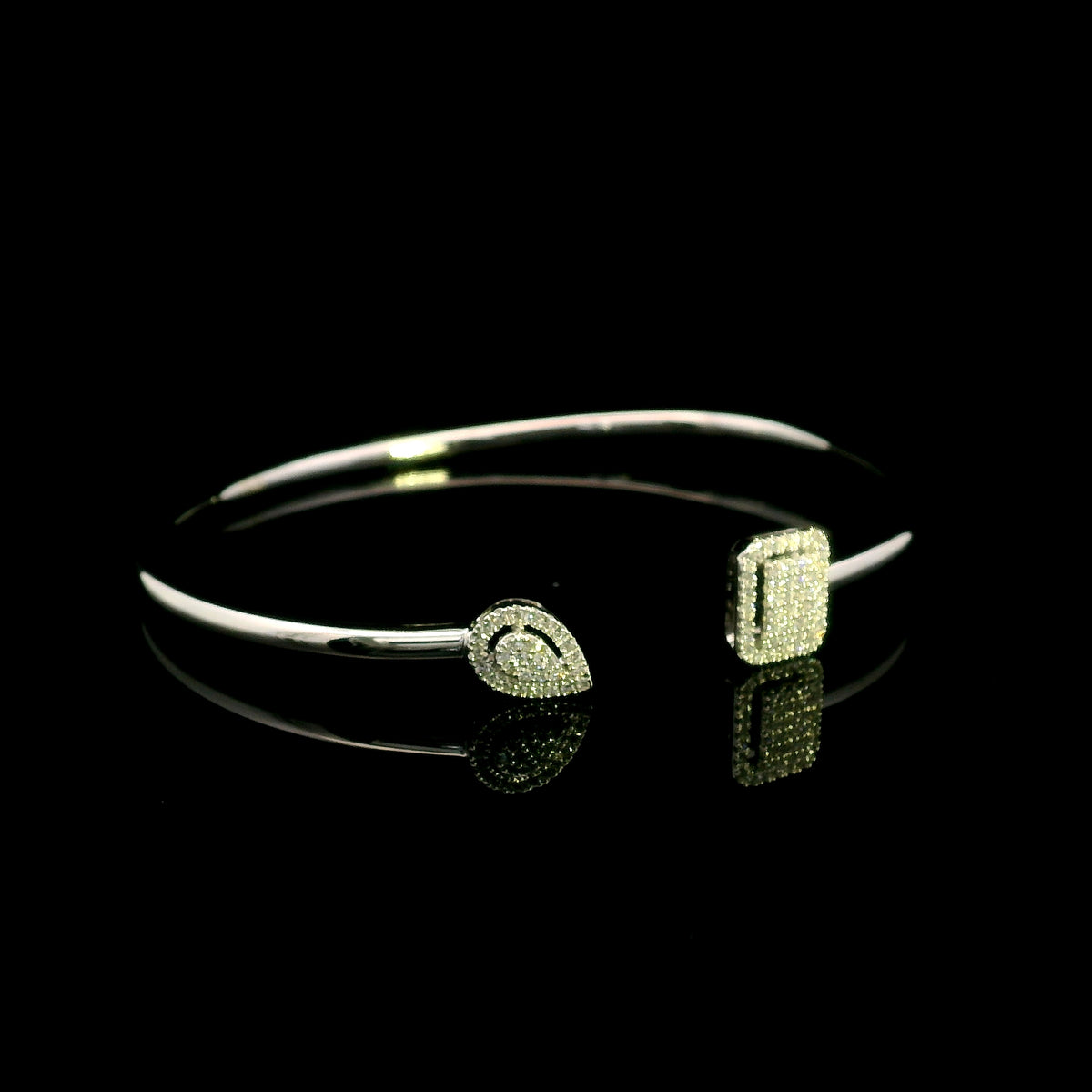 Geometric diamond open bangle in 18K white gold with contrasting pear-shaped and rectangular diamond motifs.