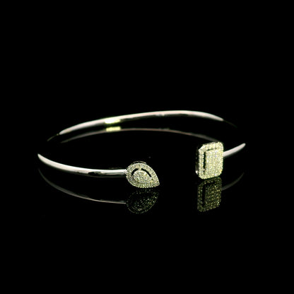 Geometric diamond open bangle in 18K white gold with contrasting pear-shaped and rectangular diamond motifs.