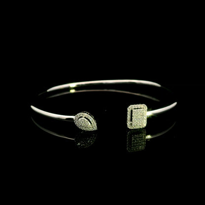 Geometric diamond open bangle in 18K white gold with contrasting pear-shaped and rectangular diamond motifs.