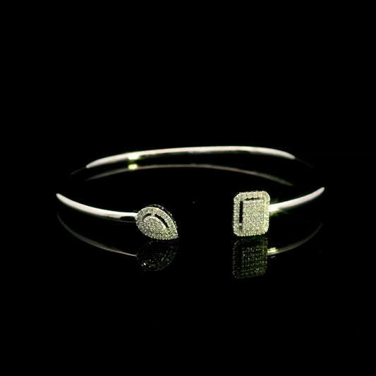 Geometric diamond open bangle in 18K white gold with contrasting pear-shaped and rectangular diamond motifs.