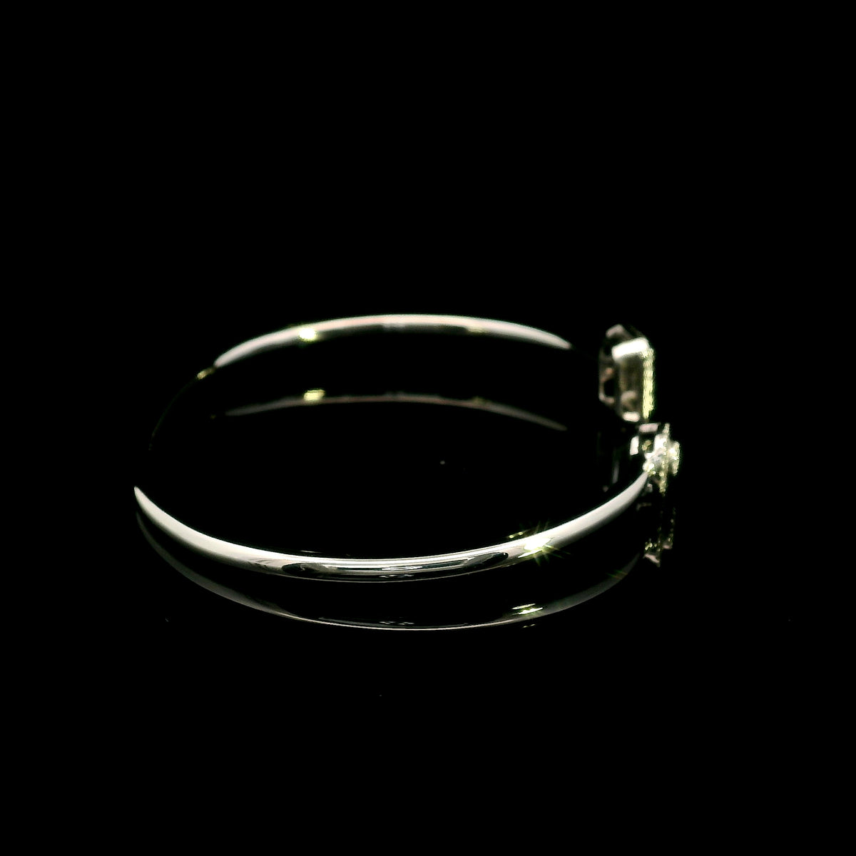 Geometric diamond open bangle in 18K white gold with contrasting pear-shaped and rectangular diamond motifs.