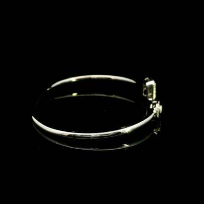 Geometric diamond open bangle in 18K white gold with contrasting pear-shaped and rectangular diamond motifs.