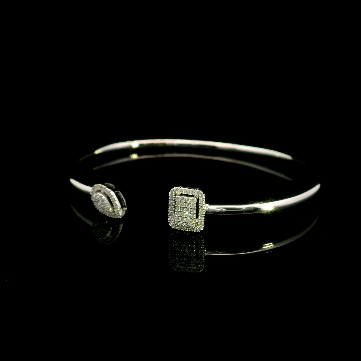 Geometric diamond open bangle in 18K white gold with contrasting pear-shaped and rectangular diamond motifs.