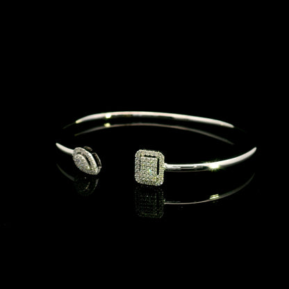 Geometric diamond open bangle in 18K white gold with contrasting pear-shaped and rectangular diamond motifs.