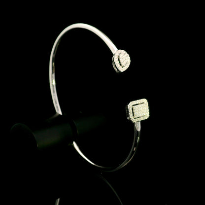 Geometric diamond open bangle in 18K white gold with contrasting pear-shaped and rectangular diamond motifs.