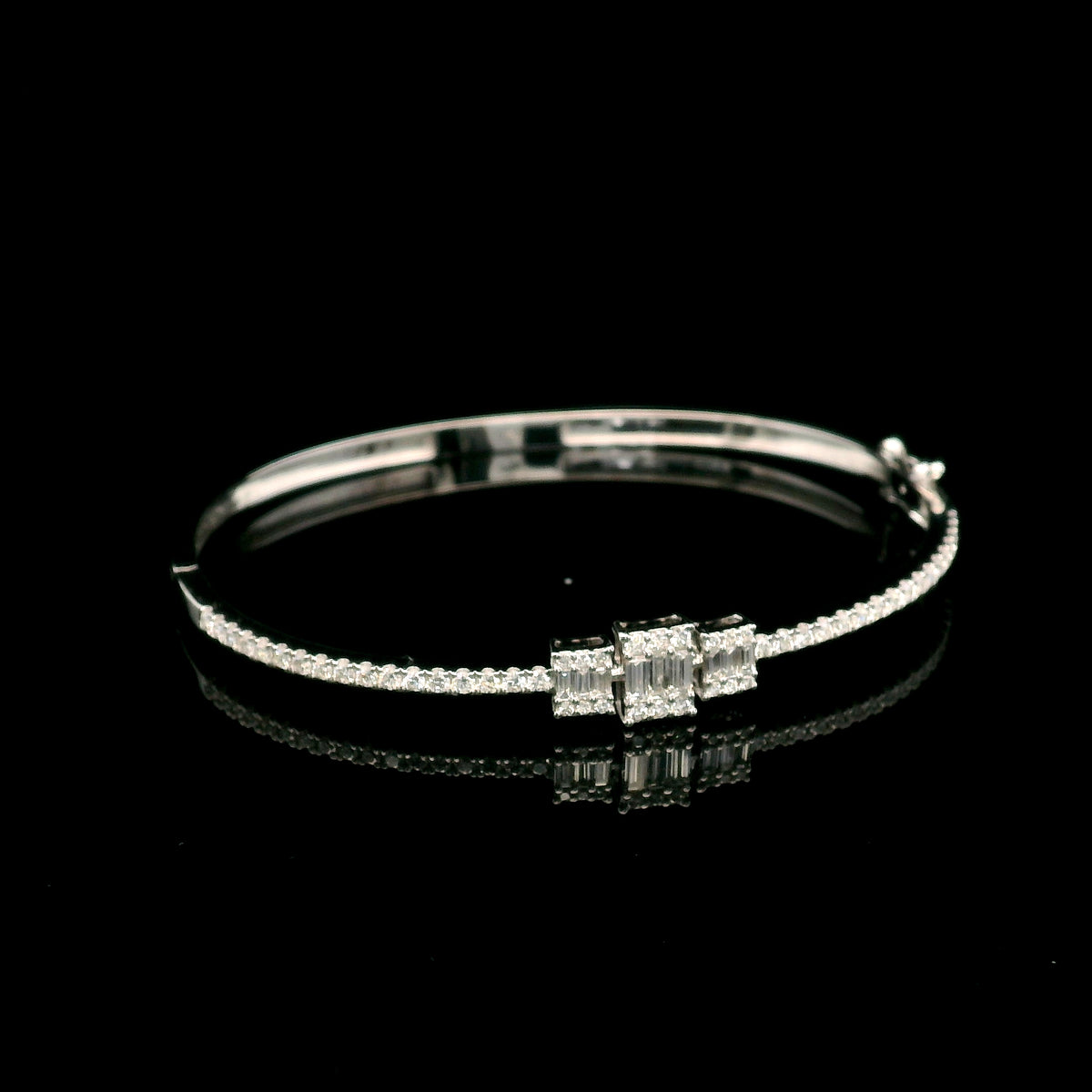 Baguette and round diamond bangle in 18K white gold with three geometric diamond centre motifs.