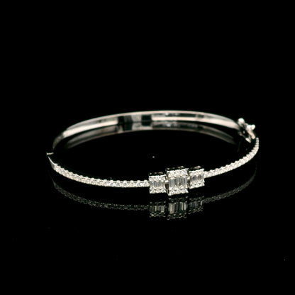 Baguette and round diamond bangle in 18K white gold with three geometric diamond centre motifs.