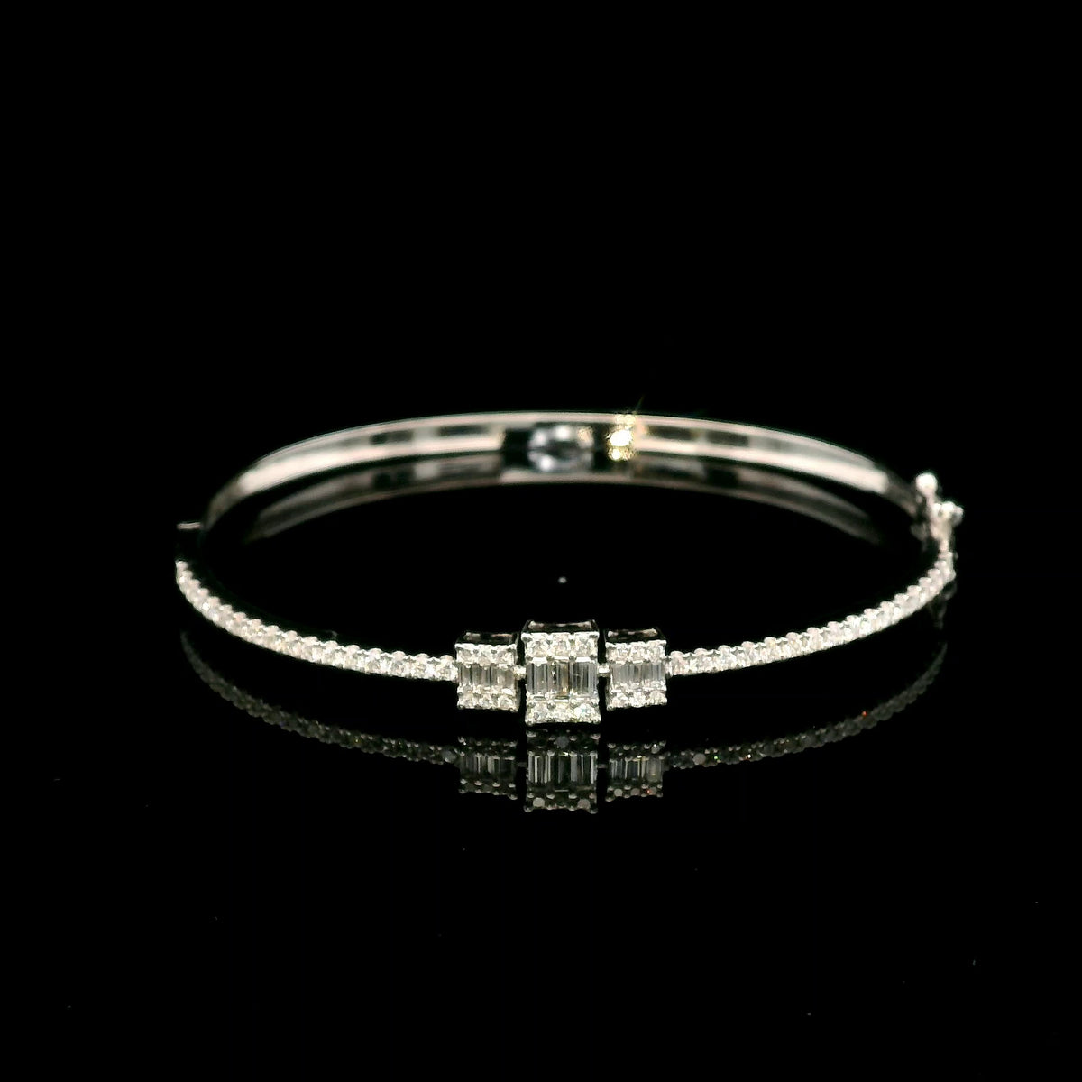 Baguette and round diamond bangle in 18K white gold with three geometric diamond centre motifs.