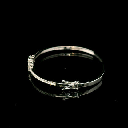 Baguette and round diamond bangle in 18K white gold with three geometric diamond centre motifs.