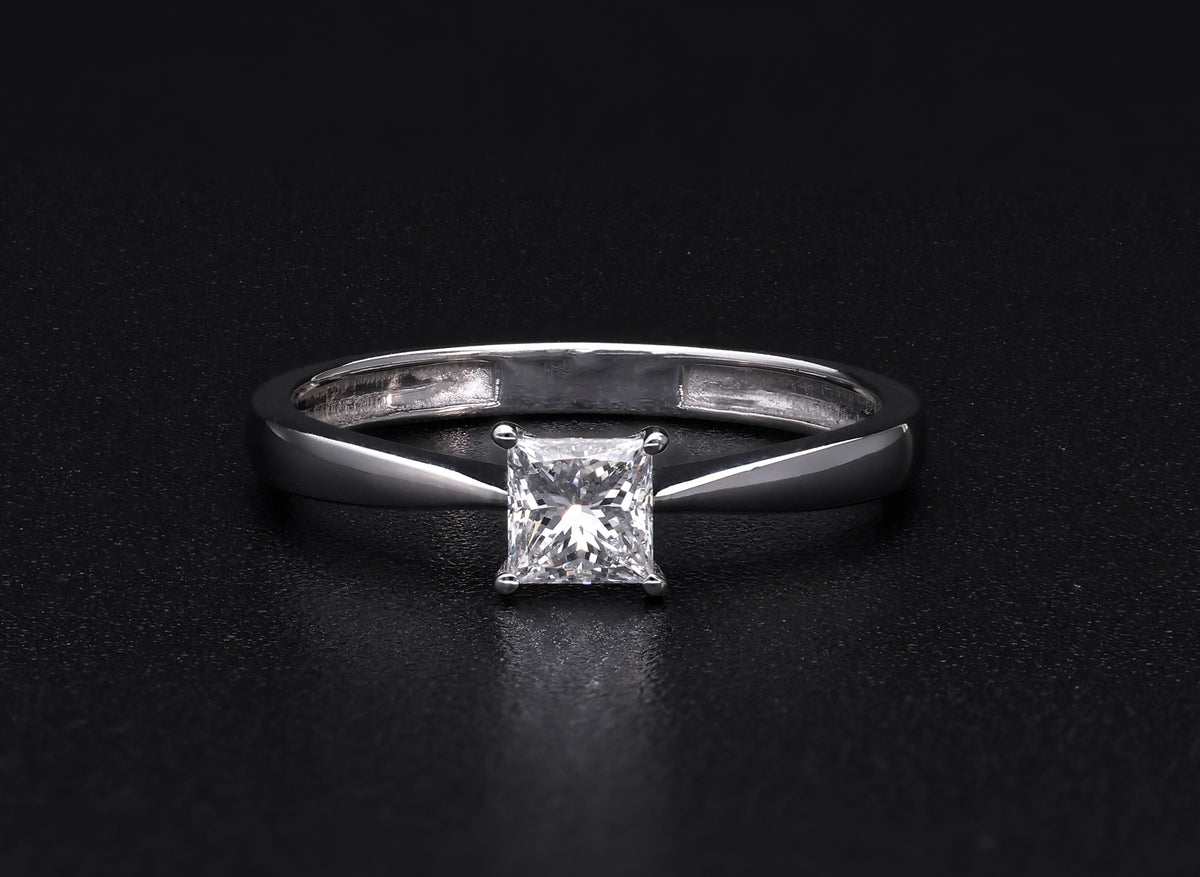 Princess cut diamond solitaire engagement ring in 18K white gold featuring a square diamond in a four-prong setting with a polished band.