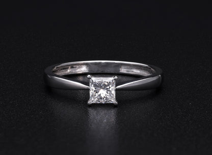 Princess cut diamond solitaire engagement ring in 18K white gold featuring a square diamond in a four-prong setting with a polished band.