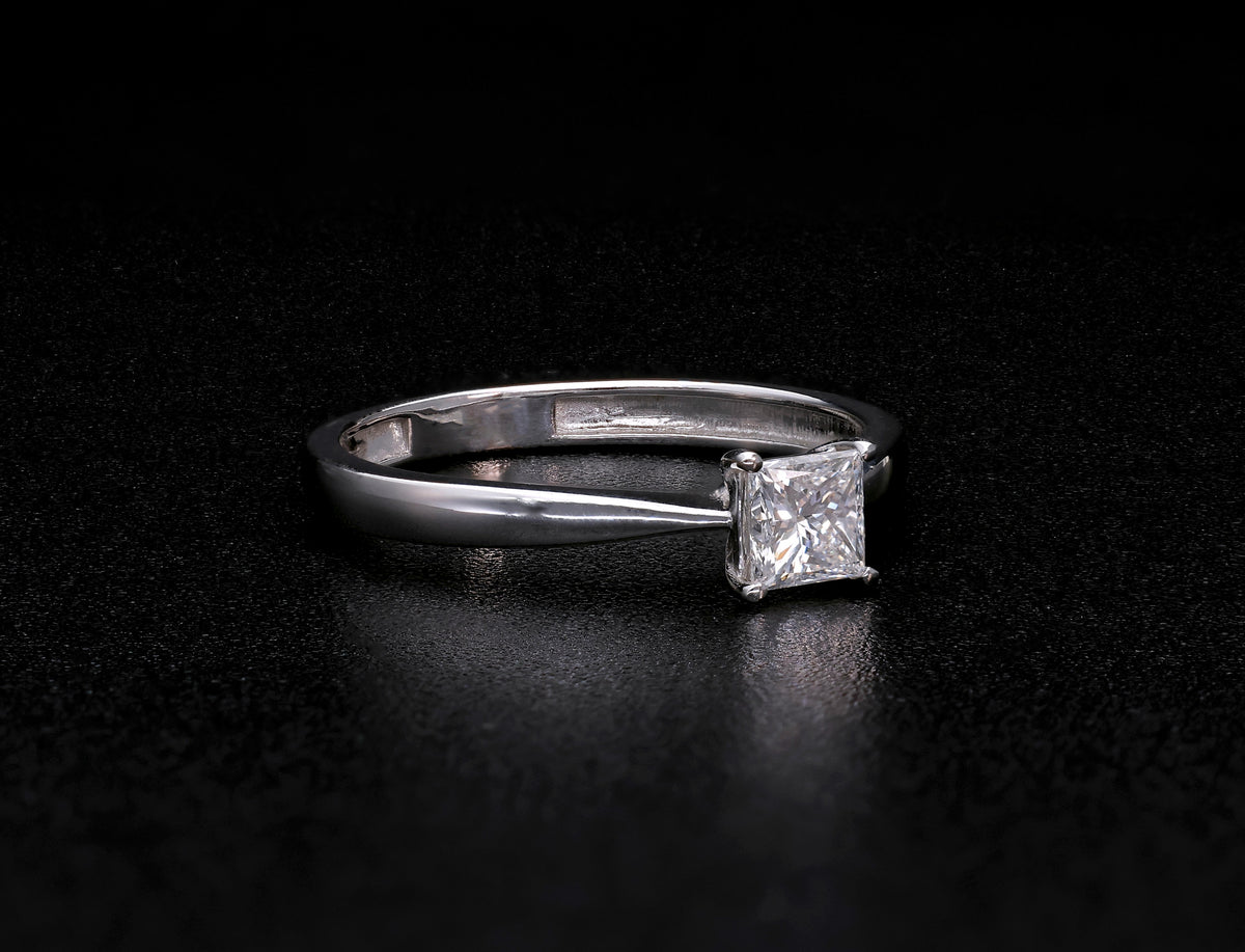 Princess cut diamond solitaire engagement ring in 18K white gold featuring a square diamond in a four-prong setting with a polished band.