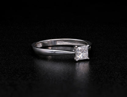 Princess cut diamond solitaire engagement ring in 18K white gold featuring a square diamond in a four-prong setting with a polished band.
