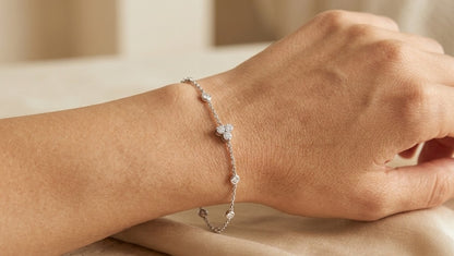 18K white gold diamond station bracelet featuring a central three-diamond cluster and four bezel-set round diamond stations along a delicate chain.