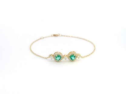 18K gold bracelet featuring two heart-shaped emeralds (0.57ct) with diamond halos (0.38ct) on a delicate chain.