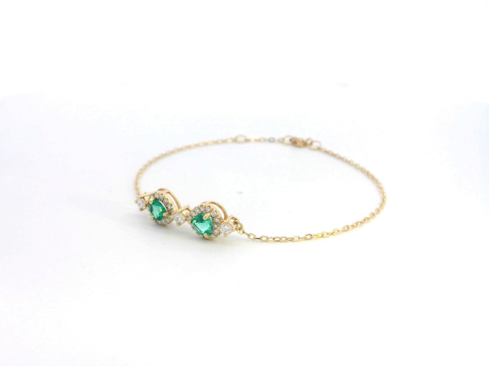 18K gold bracelet featuring two heart-shaped emeralds (0.57ct) with diamond halos (0.38ct) on a delicate chain.