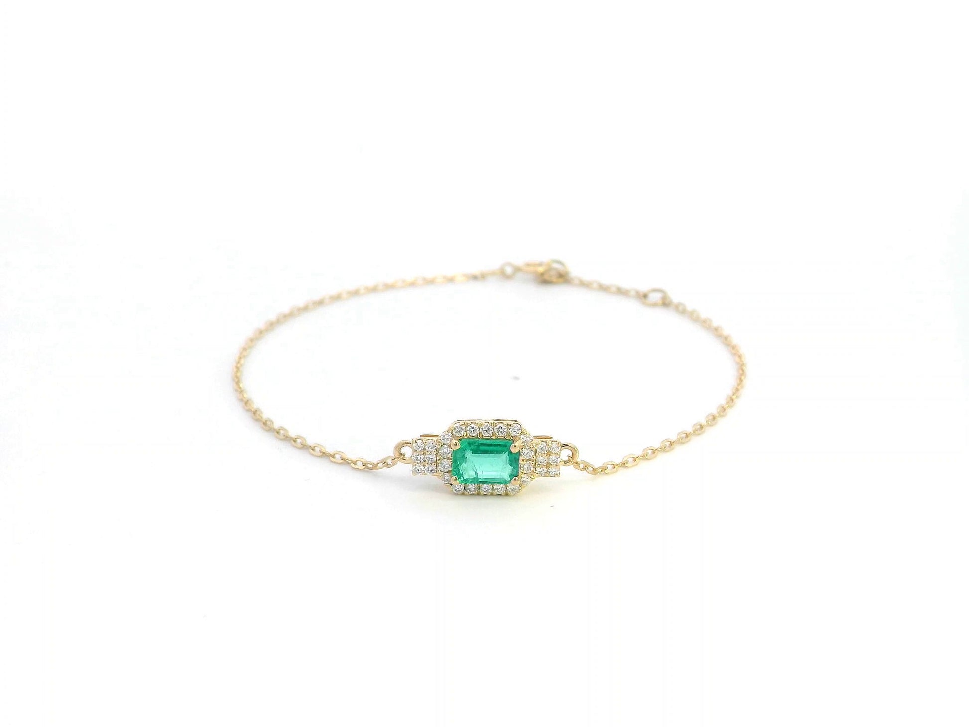 Elegant 18K gold emerald bracelet featuring a 0.48-carat emerald centerpiece with a halo of 0.17-carat diamonds on a delicate gold chain.