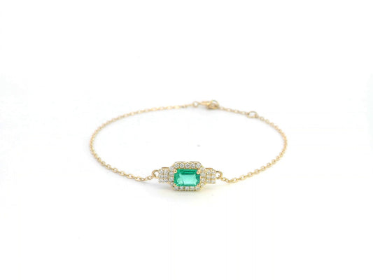 Elegant 18K gold emerald bracelet featuring a 0.48-carat emerald centerpiece with a halo of 0.17-carat diamonds on a delicate gold chain.