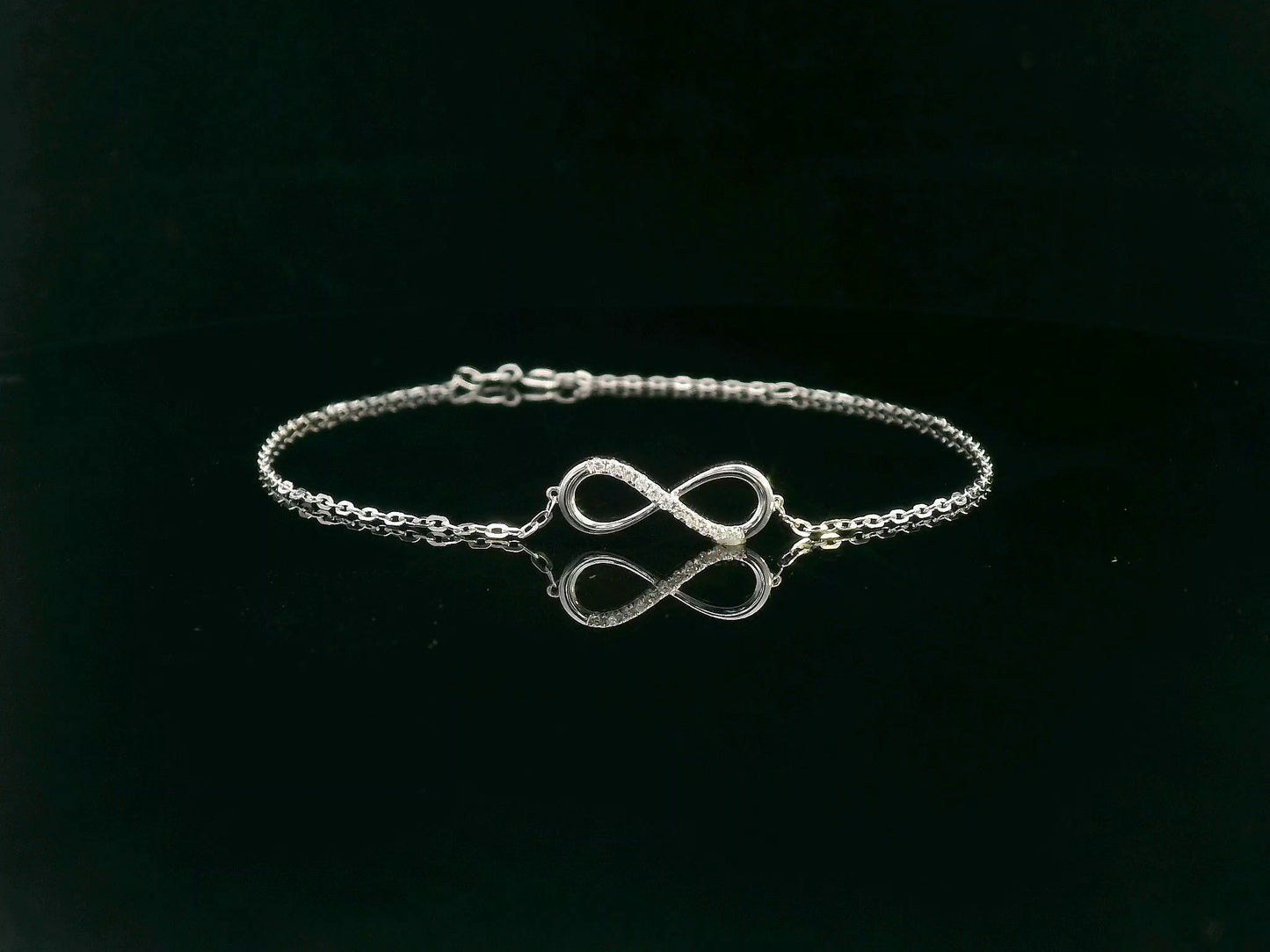 18K white gold infinity bracelet with 0.05 carat diamonds on delicate chain, half polished and half pavé-set