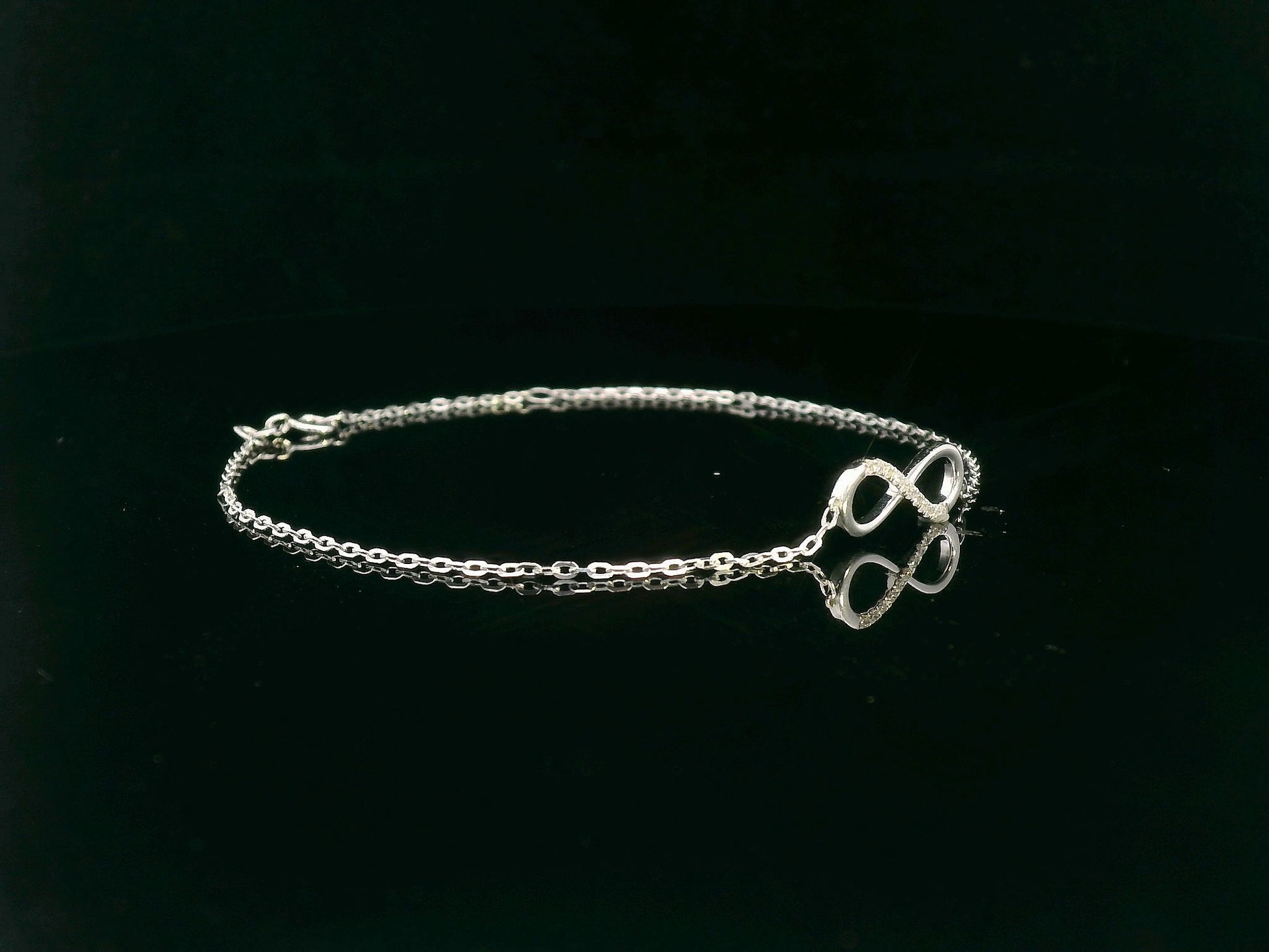 18K white gold infinity bracelet with 0.05 carat diamonds on delicate chain, half polished and half pavé-set