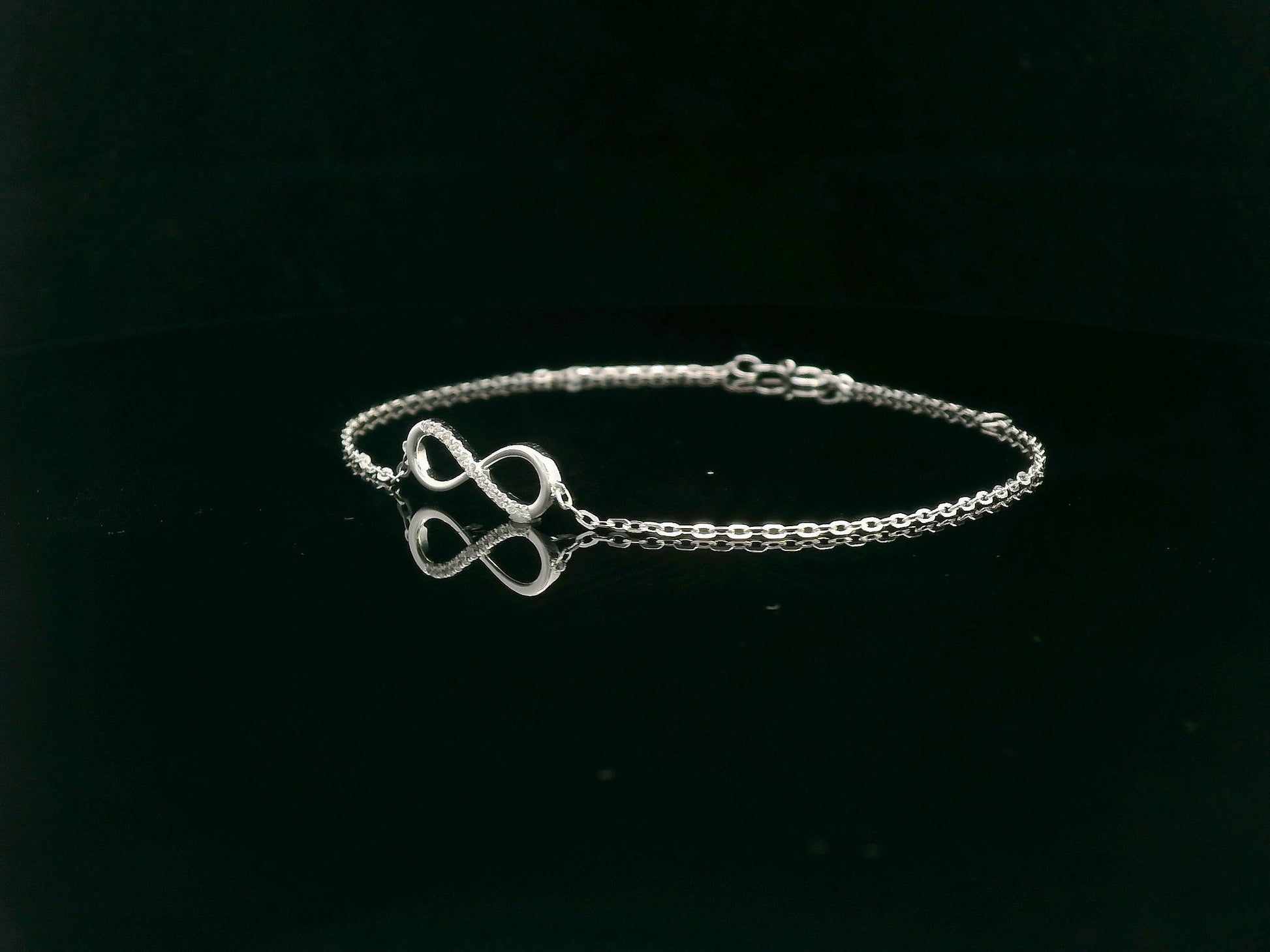 18K white gold infinity bracelet with 0.05 carat diamonds on delicate chain, half polished and half pavé-set