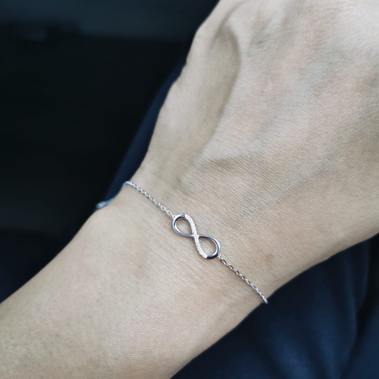 18K white gold infinity bracelet with 0.05 carat diamonds on delicate chain, half polished and half pavé-set