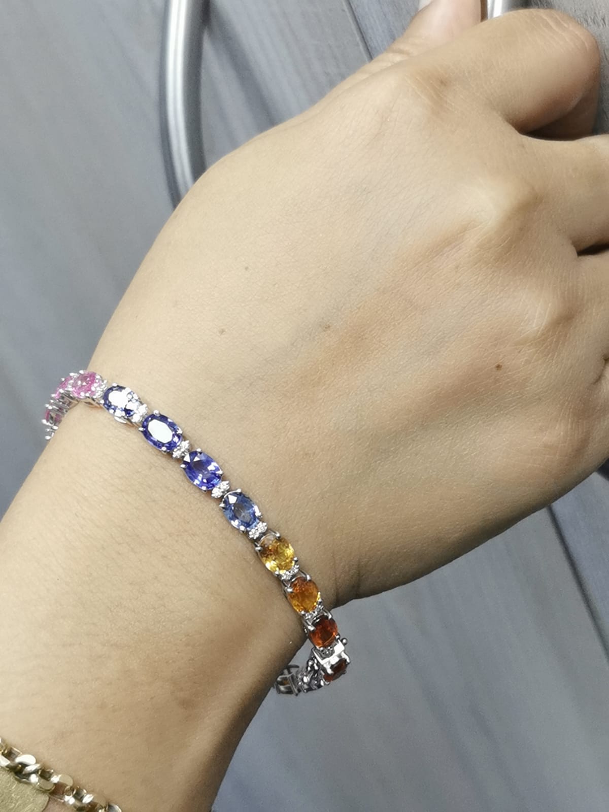 Multicolored gemstone bracelet on a wrist with a neutral background