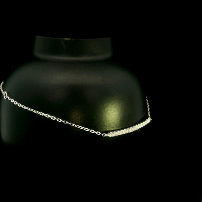 Diamond bar bracelet in 18K white gold featuring a curved row of round brilliant diamonds on a fine chain.