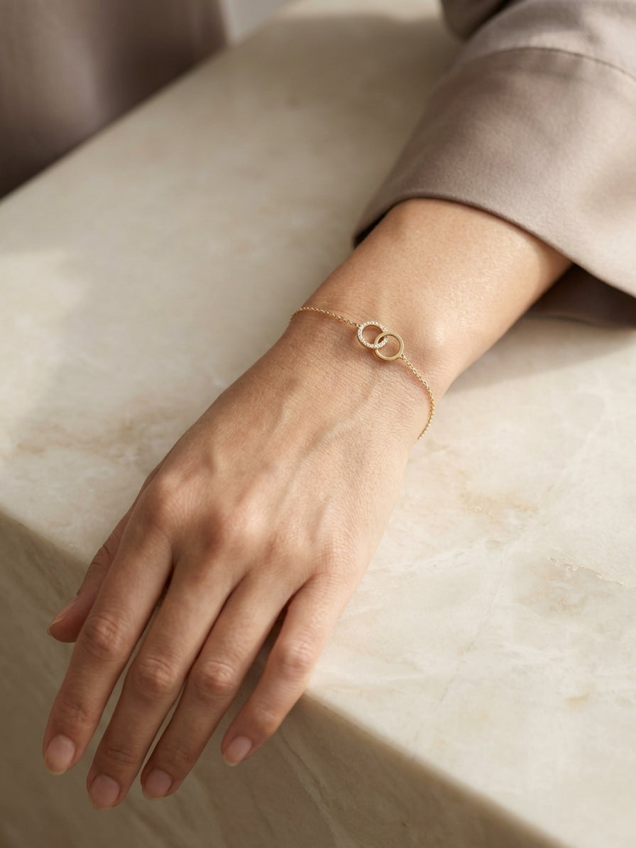 18K yellow gold diamond circle bracelet with two interlocking rings, featuring one polished gold circle and one round diamond-set circle