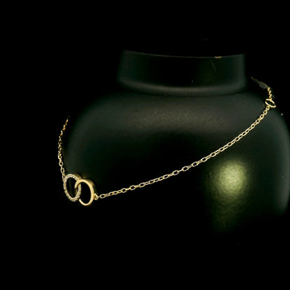 18K yellow gold diamond circle bracelet with two interlocking rings, featuring one polished gold circle and one round diamond-set circle
