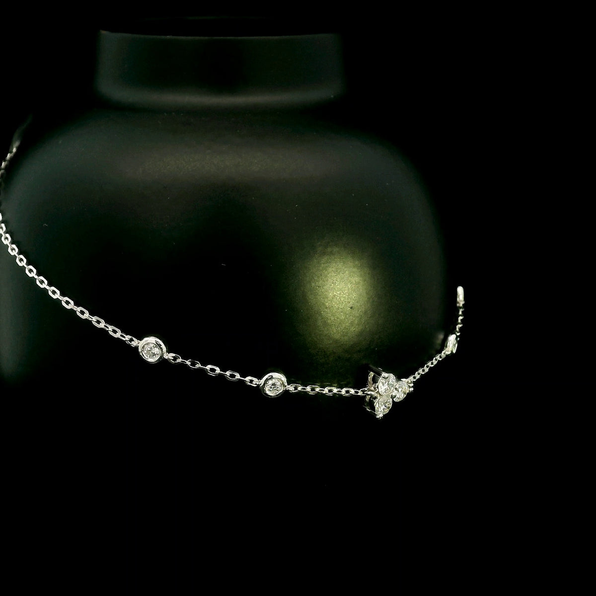 18K white gold diamond station bracelet featuring a central three-diamond cluster and four bezel-set round diamond stations along a delicate chain.
