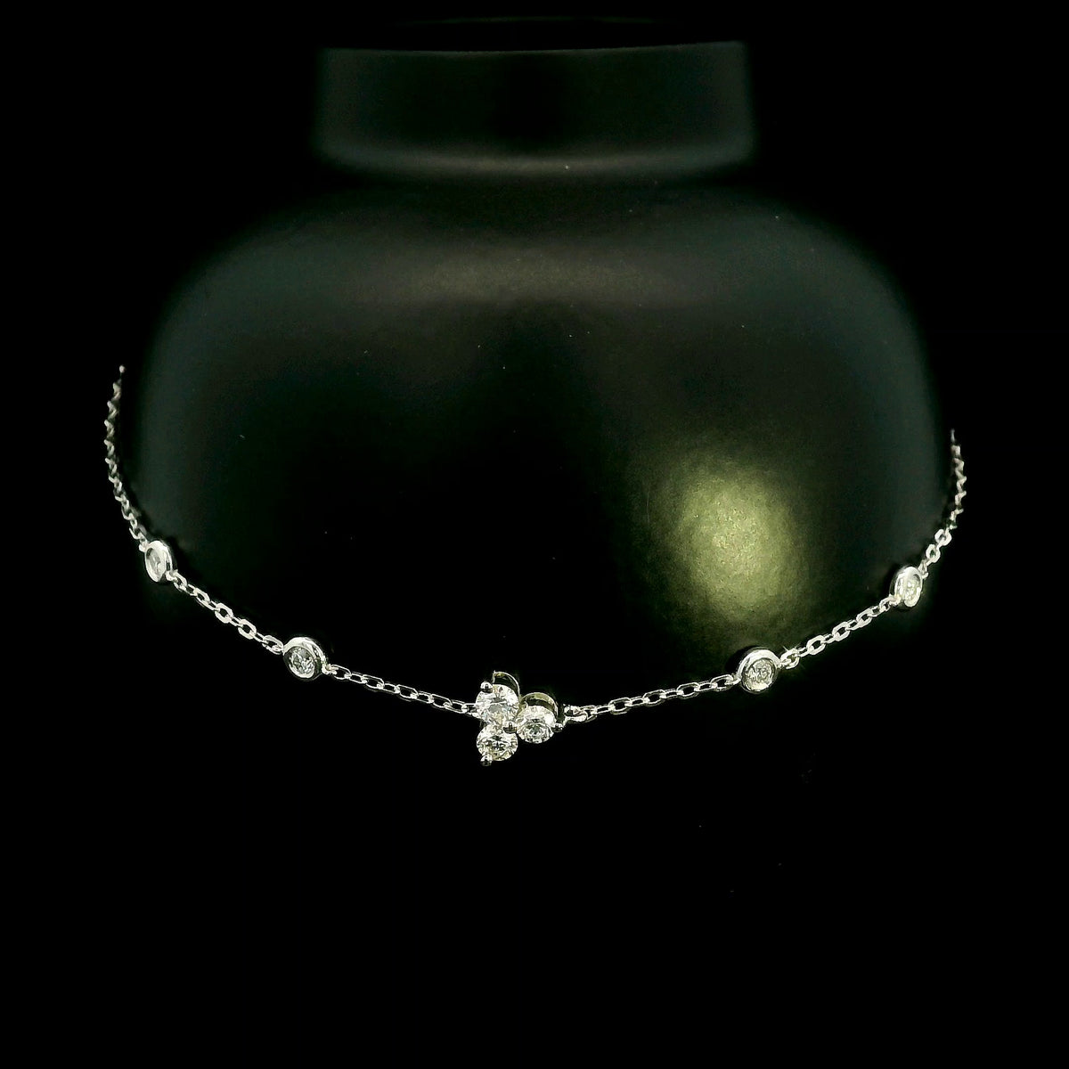 18K white gold diamond station bracelet featuring a central three-diamond cluster and four bezel-set round diamond stations along a delicate chain.