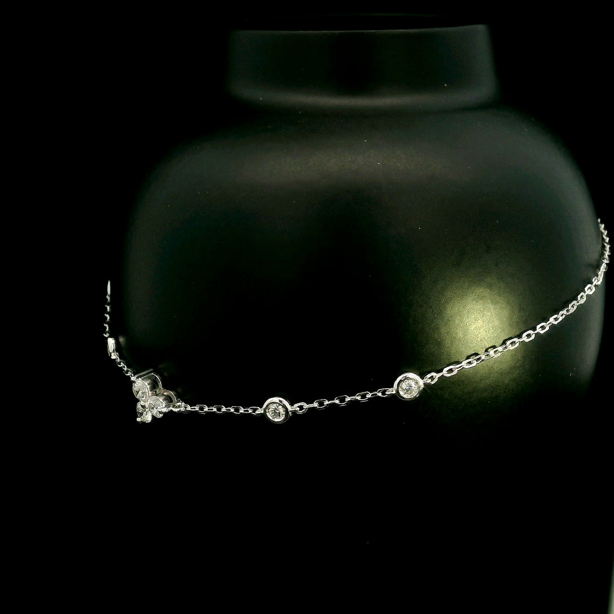 18K white gold diamond station bracelet featuring a central three-diamond cluster and four bezel-set round diamond stations along a delicate chain.