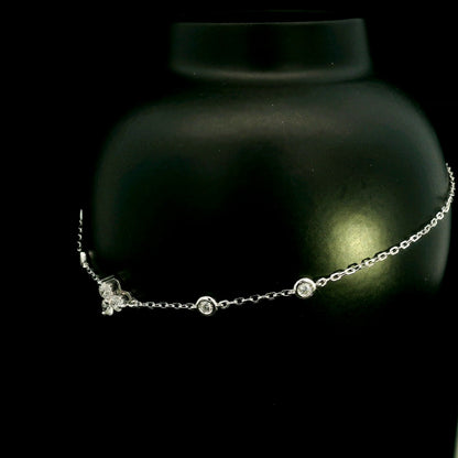 18K white gold diamond station bracelet featuring a central three-diamond cluster and four bezel-set round diamond stations along a delicate chain.