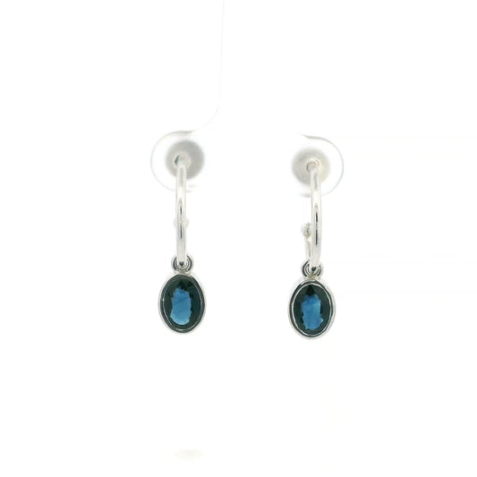Oval blue sapphire drop hoop earrings in 18K white gold with polished hoops and suspended sapphire drops.