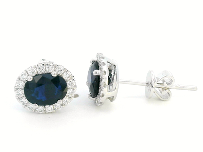 18K gold stud earrings featuring 1.88 carat oval blue sapphires and a 0.33 carat diamond halo, perfect for September birthstone jewelry.