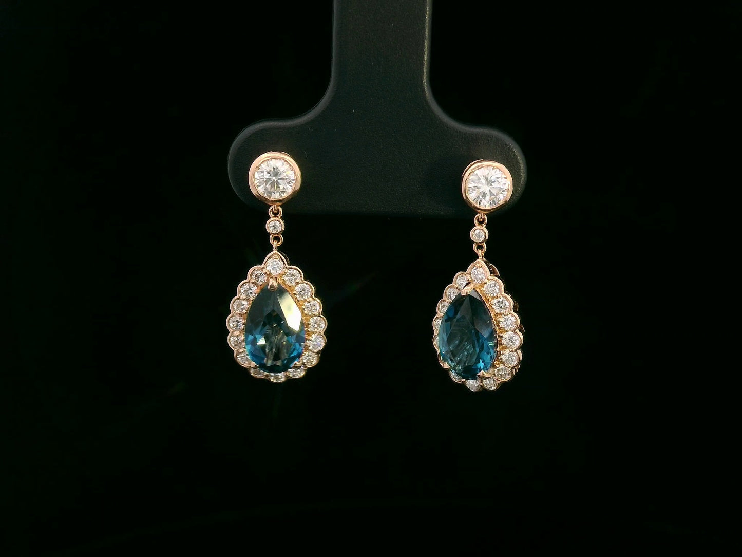 Elegant 18K gold pear-cut London blue topaz and diamond halo drop earrings featuring 2.00 carats of topaz and 0.66 carats of diamonds.