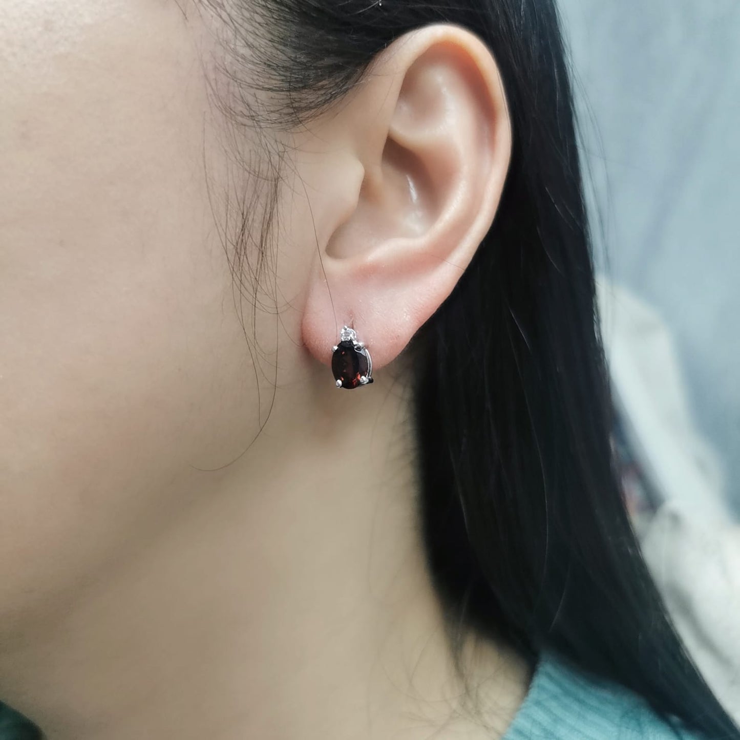 18K white gold garnet and diamond stud earrings featuring oval-cut 3.09-carat garnets with 0.07-carat diamond accents, set in a classic four-prong setting with push-back closures.