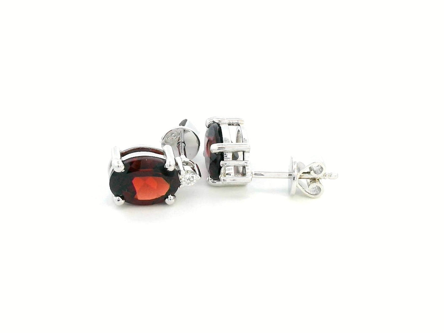 18K white gold garnet and diamond stud earrings featuring oval-cut 3.09-carat garnets with 0.07-carat diamond accents, set in a classic four-prong setting with push-back closures.