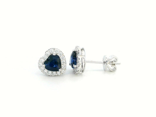 18K white gold heart-shaped sapphire and diamond halo stud earrings featuring a 1.40-carat deep blue sapphire and 0.33-carat round diamonds, perfect for fine jewelry lovers, birthdays, and September birthstone gifts.