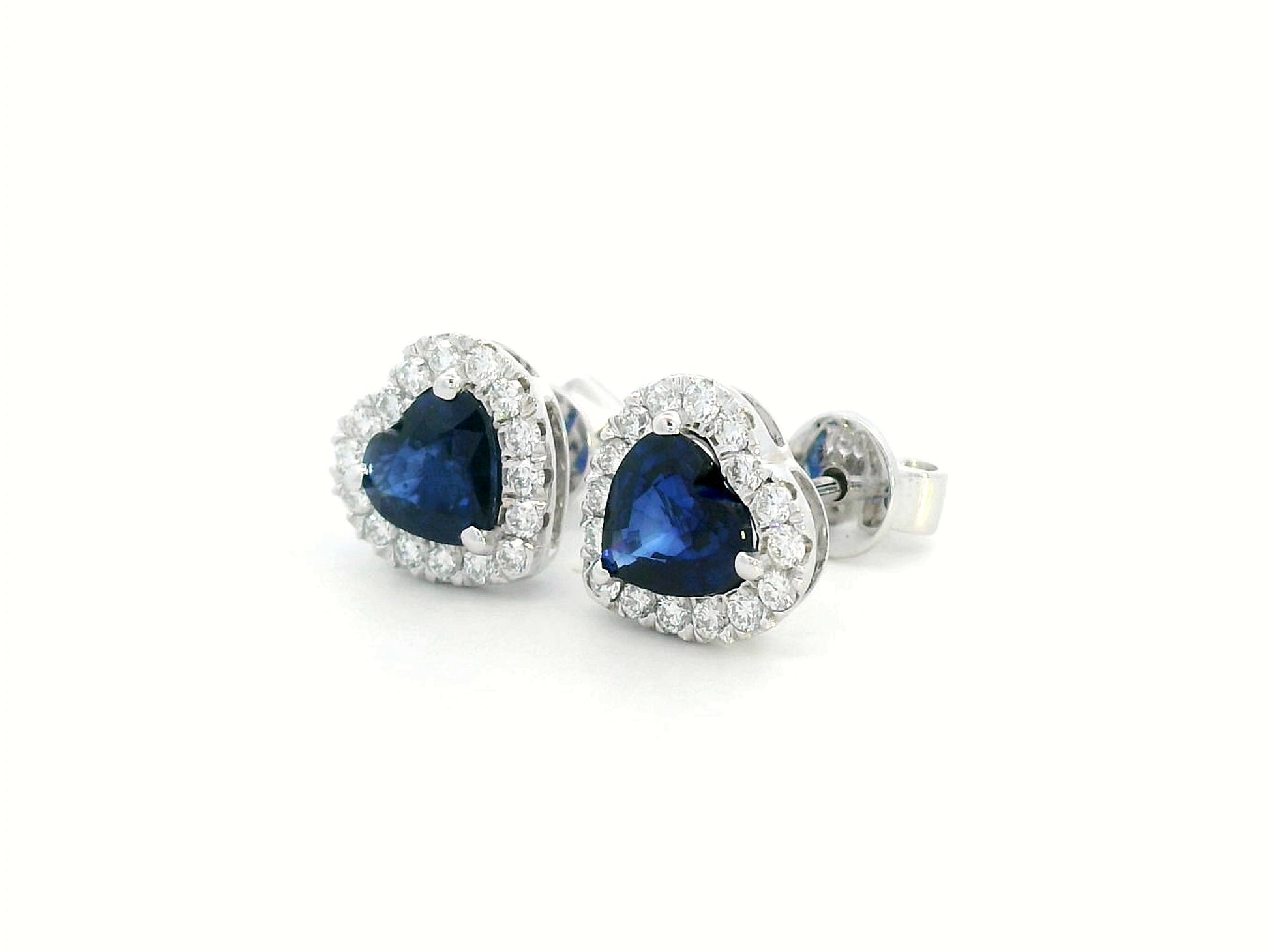 18K white gold heart-shaped sapphire and diamond halo stud earrings featuring a 1.40-carat deep blue sapphire and 0.33-carat round diamonds, perfect for fine jewelry lovers, birthdays, and September birthstone gifts.