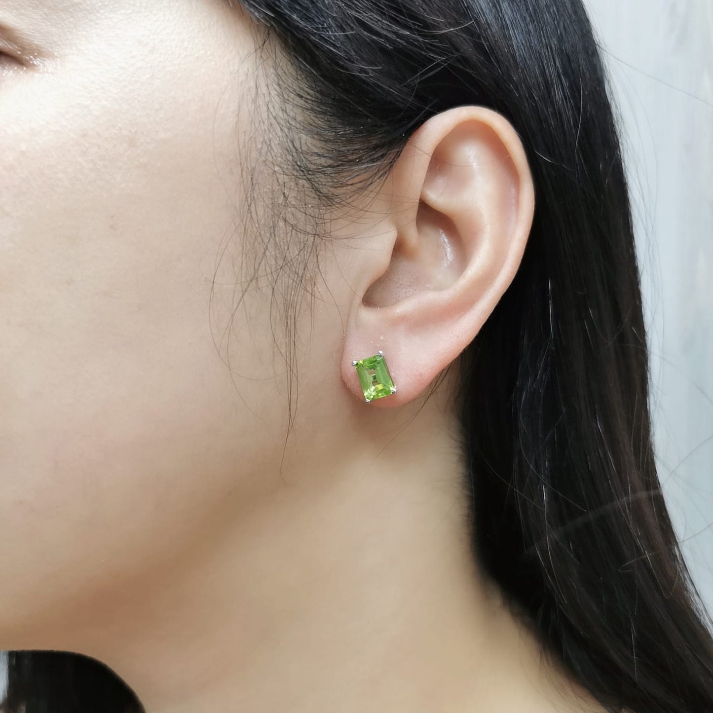 Emerald cut Peridot earrings in 18K white gold, featuring 3.30 carats of vibrant green gemstones in a four-prong setting, symbolizing strength and renewal for those born in August