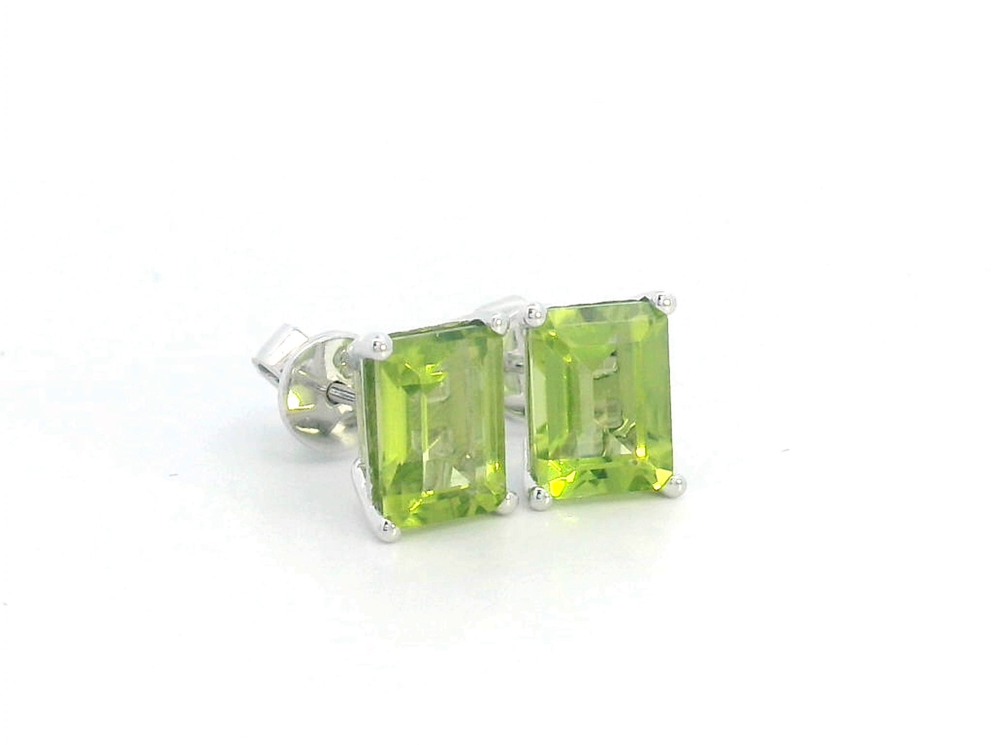 Emerald cut Peridot earrings in 18K white gold, featuring 3.30 carats of vibrant green gemstones in a four-prong setting, symbolizing strength and renewal for those born in August