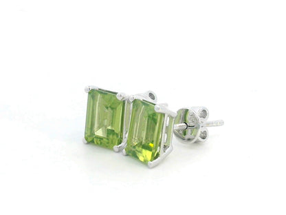 Emerald cut Peridot earrings in 18K white gold, featuring 3.30 carats of vibrant green gemstones in a four-prong setting, symbolizing strength and renewal for those born in August