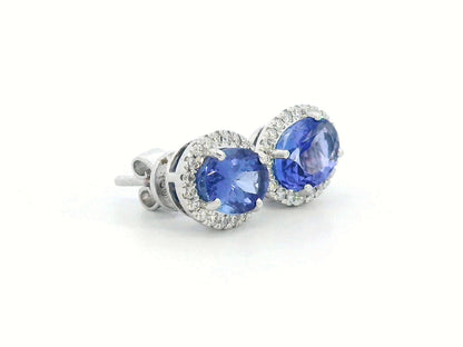 Elegant 18K white gold tanzanite and diamond halo earrings featuring 1.84ct oval tanzanites encircled by 0.19ct natural diamonds.