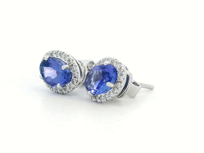 Elegant 18K white gold tanzanite and diamond halo earrings featuring 1.84ct oval tanzanites encircled by 0.19ct natural diamonds.